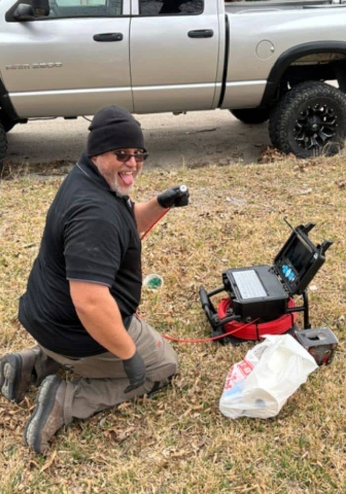 Man working with plumbing equipment outdoors.