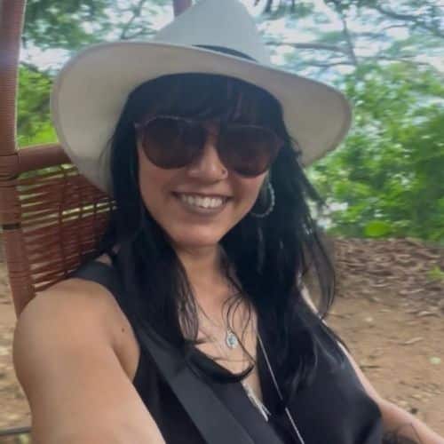 Woman smiling in a hat outdoors.
